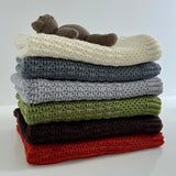 Teddy on a stack of merino bassinet blankets