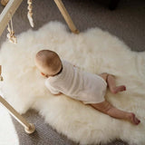 Baby on natural long wool play sheepskin baby rug