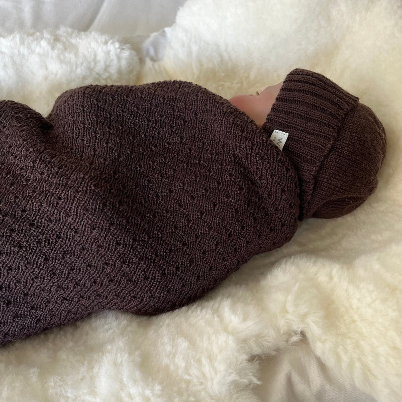 Baby asleep in knitted brown baby wrap and beanie