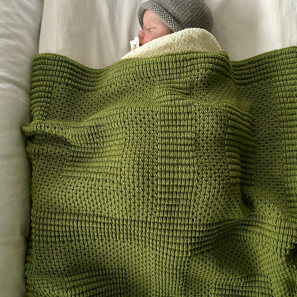 Baby asleep in moss merino pram blanket