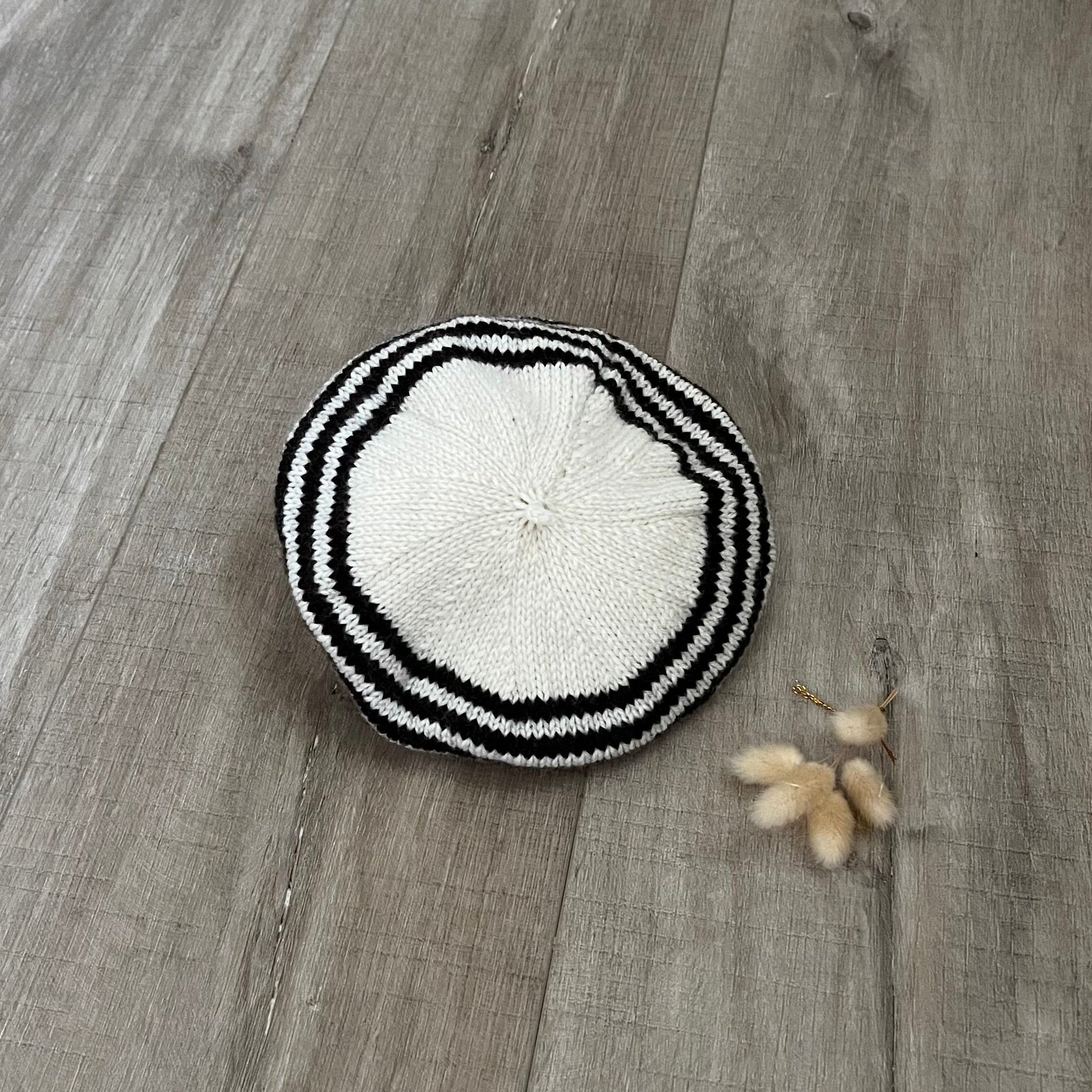 Chocolate and white knitted beret on a wooden surface
