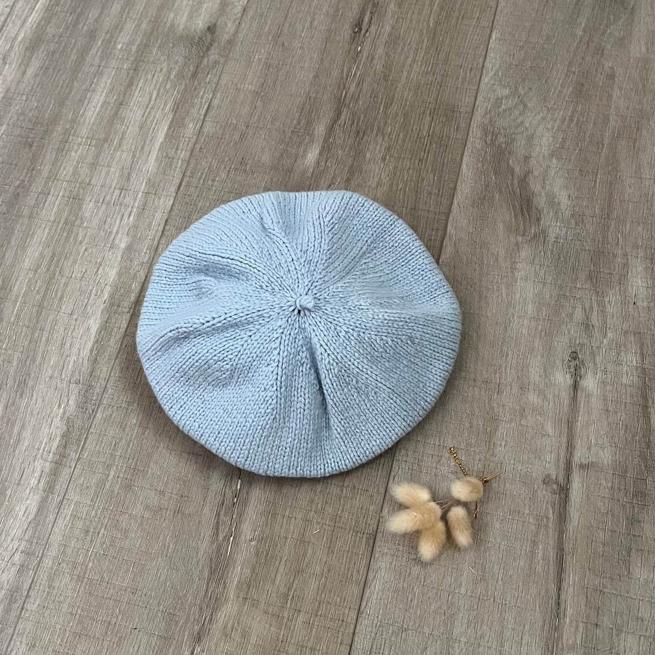 Blue knitted beret on a wooden surface