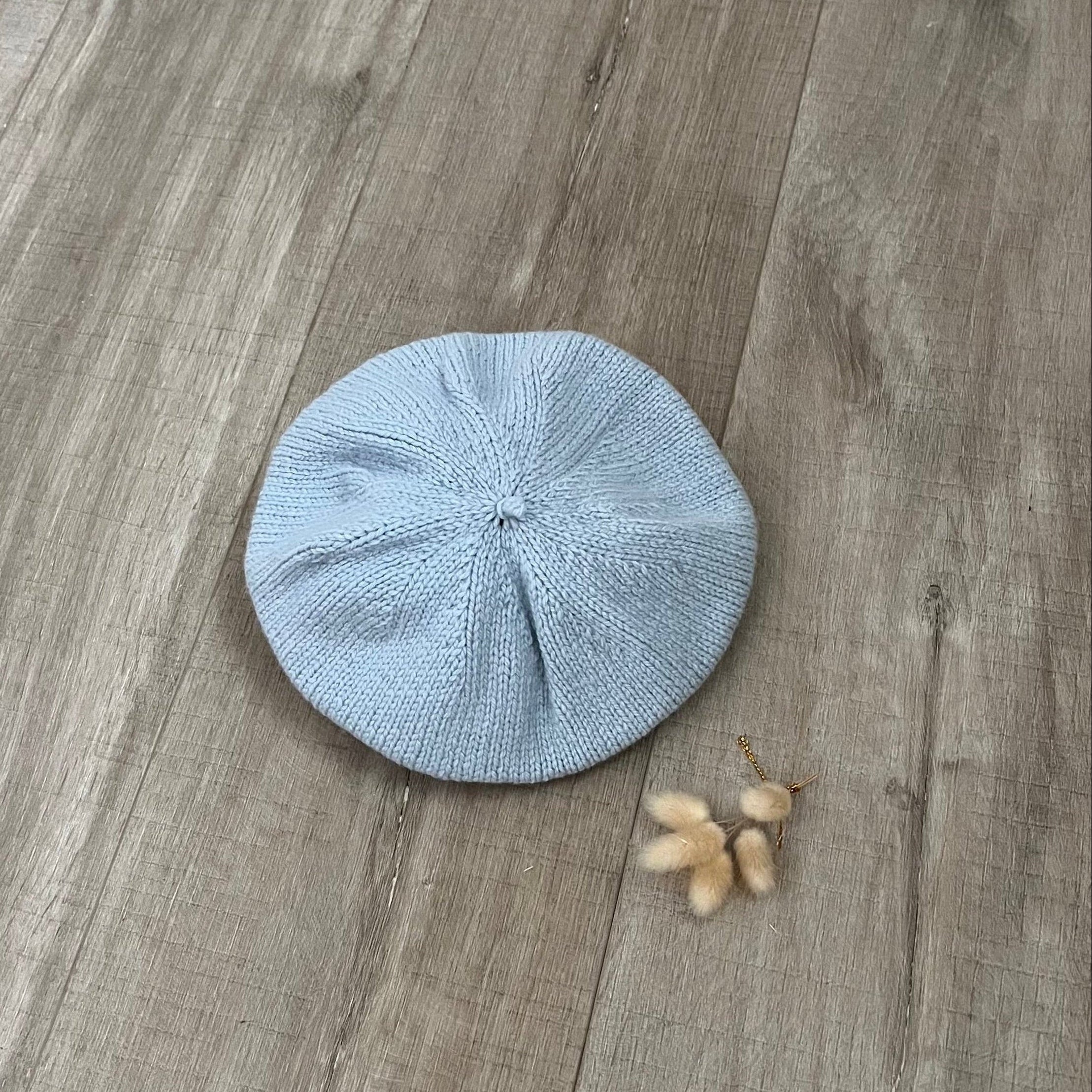 Blue knitted beret on a wooden surface