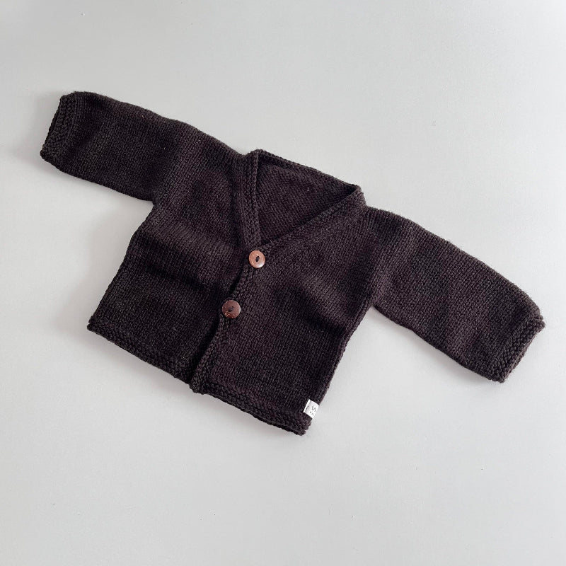 Chocolate knitted baby cardigan on a light grey background