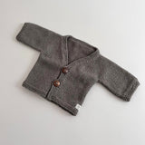 Knitted mushroom baby cardigan with buttons on a light grey background