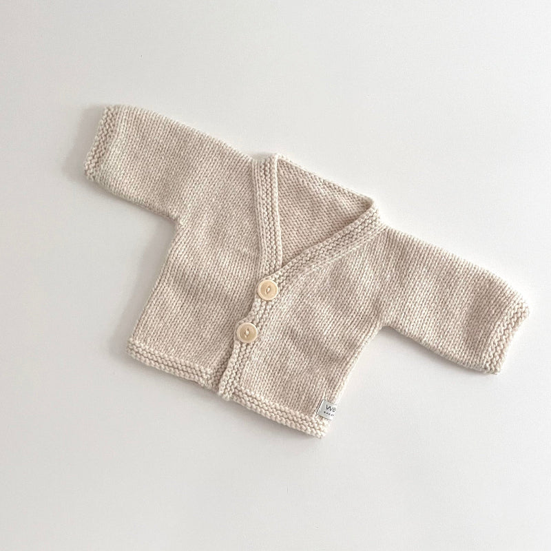 Knitted natiral baby cardigan on a light gray background