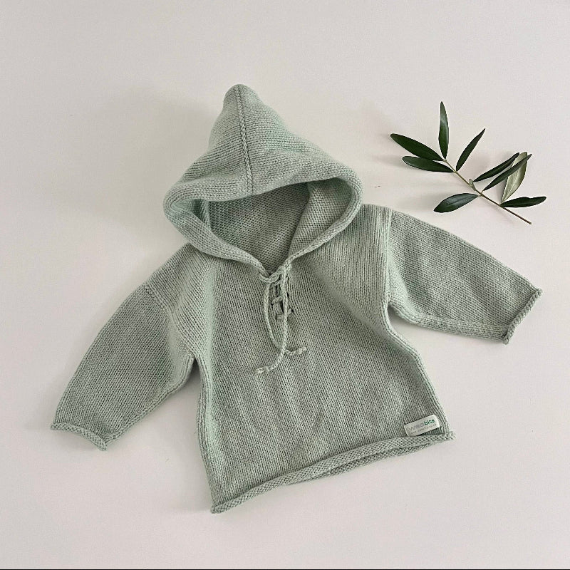 Green knitted hoodie on a light background with a leaf decoration