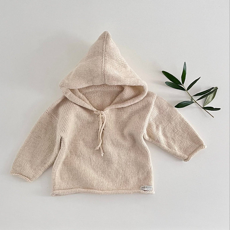 Natural knitted hoodie on a light grey background with a green leaf decoration.