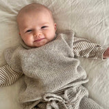 Baby in cot wearing roll neck vest and knit pants