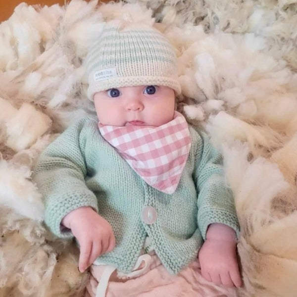 Baby in her mint baby cardigan and beanie set