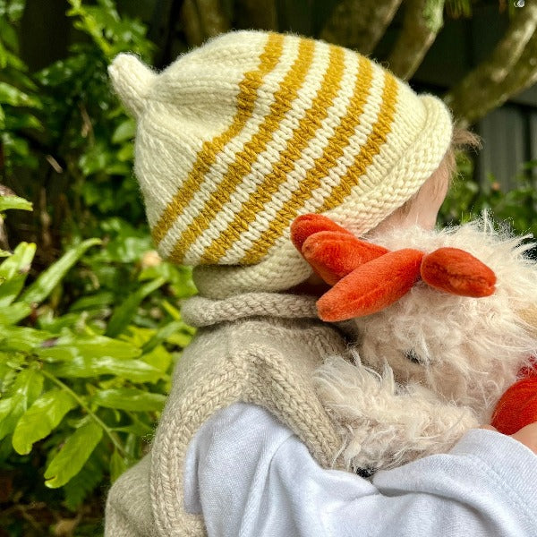 Baby in the garden wearing mustard stripe beanie