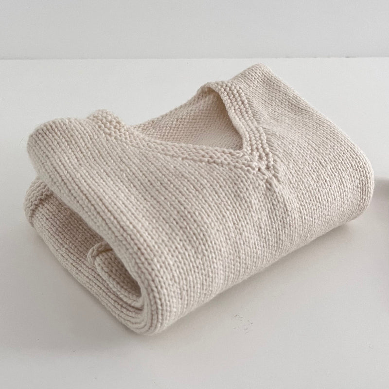 Folded natural knitted jumper on a white surface