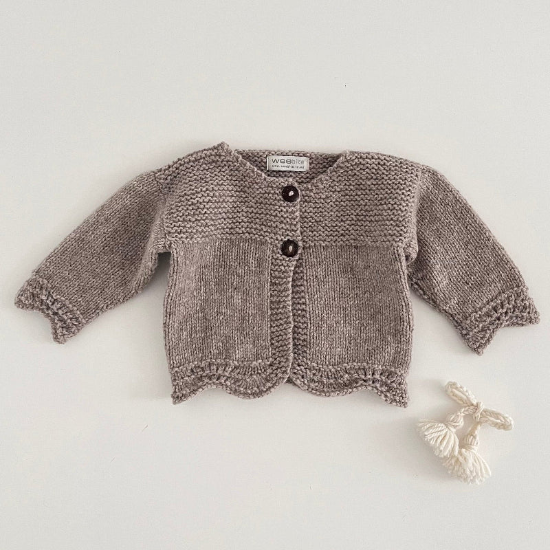 Oatmeal marle coloured knitted baby cardigan on a light grey background