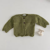Pistachio coloured knitted baby cardigan on a light grey background