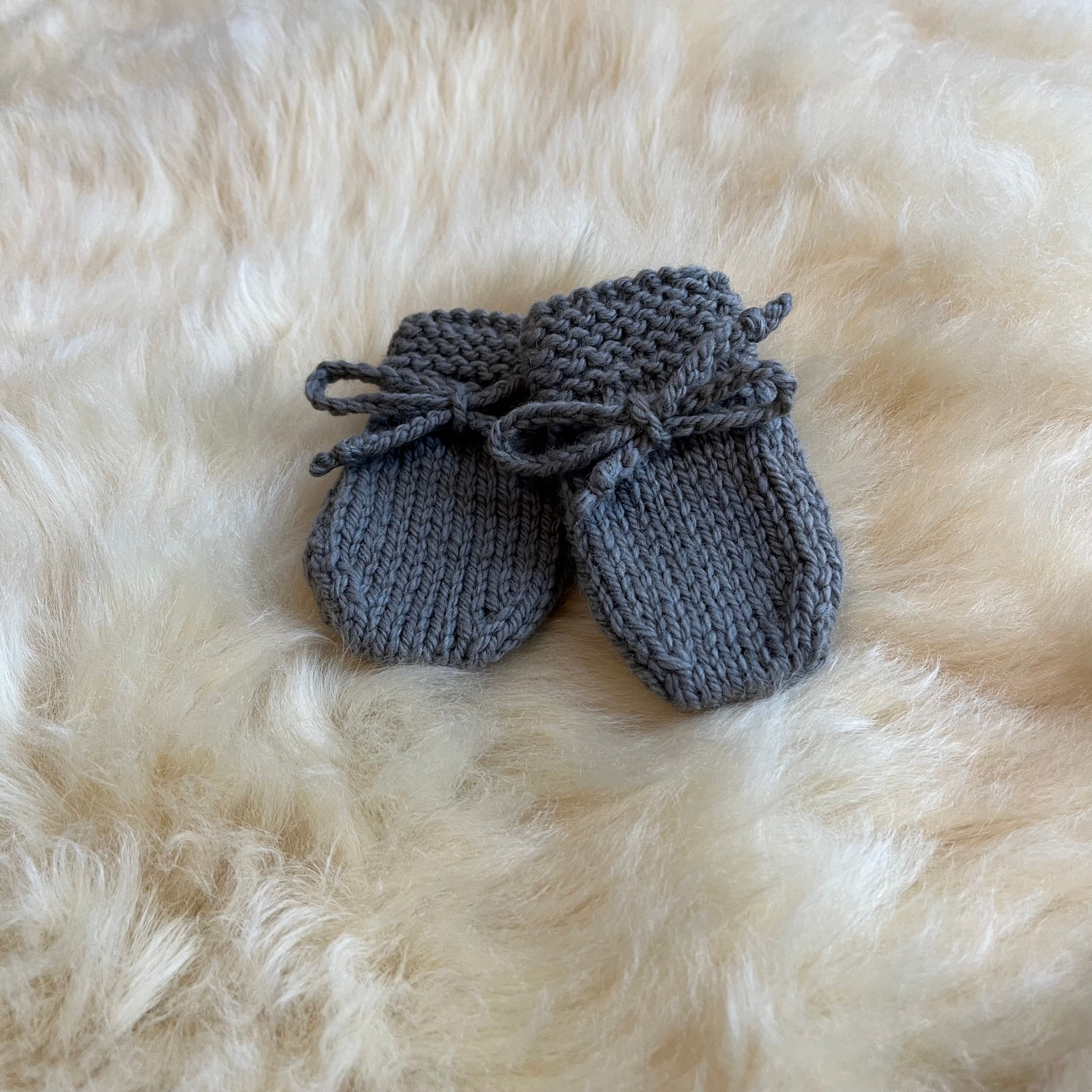 Pair of mushroom knitted baby mittens on a fluffy sheepskin rug