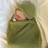 Baby sleeping in moss merino wrap and beanie