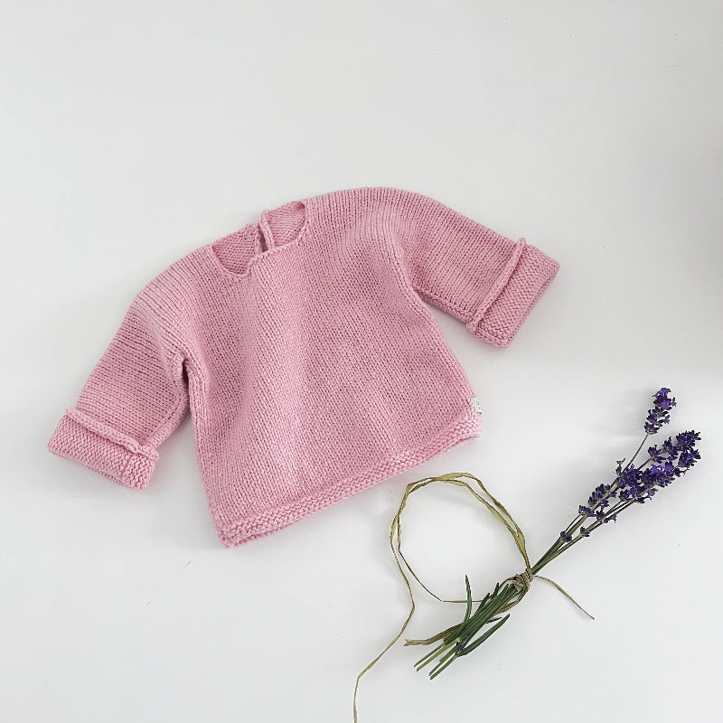 Pink knitted baby slouchy sweater on a white background with lavender flowers.