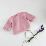 Pink knitted baby slouchy sweater on a white background with lavender flowers.