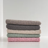 A baby travel rug in various colours on a white surface.