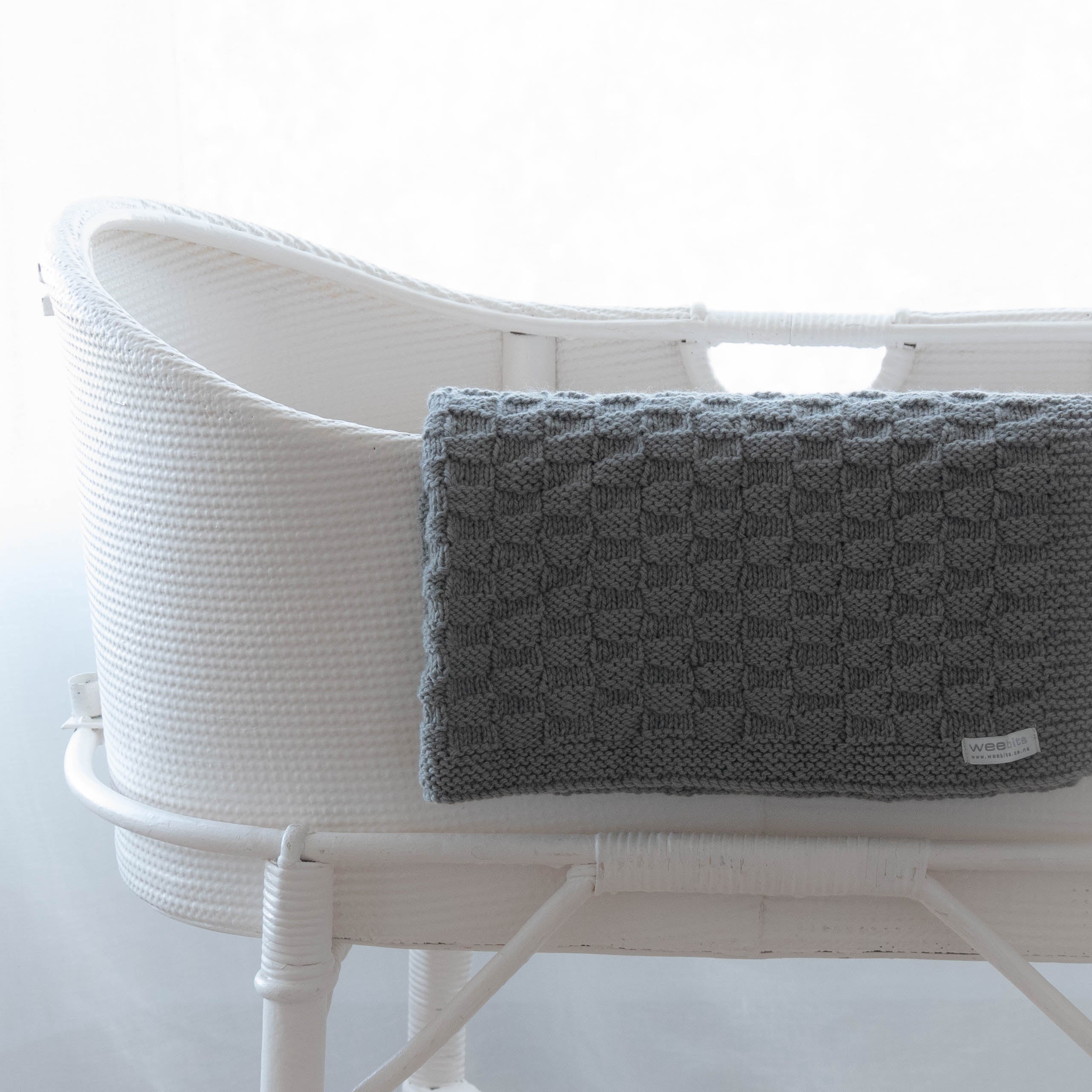 White woven basket with a mushroom textured blanket on a white background