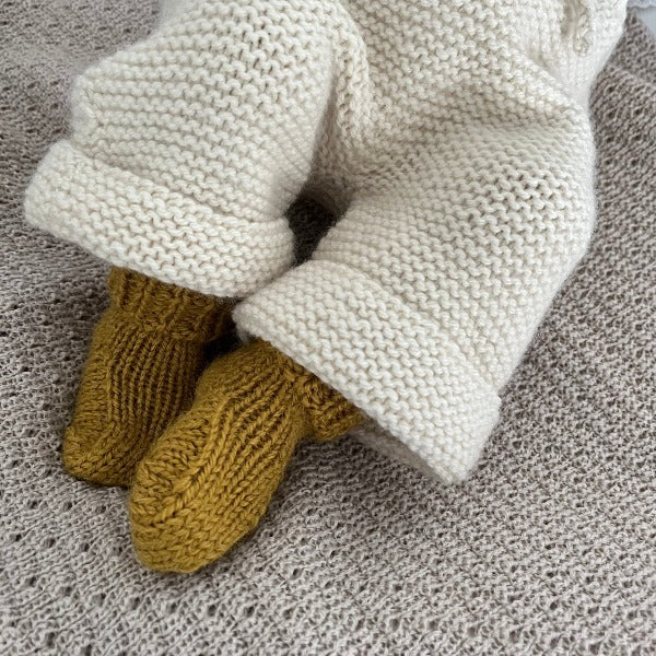 Baby wearing mustard wool socks with natural knitted pants