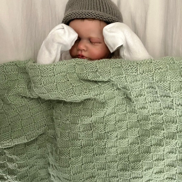 Baby wrapped in mint merino travel rug