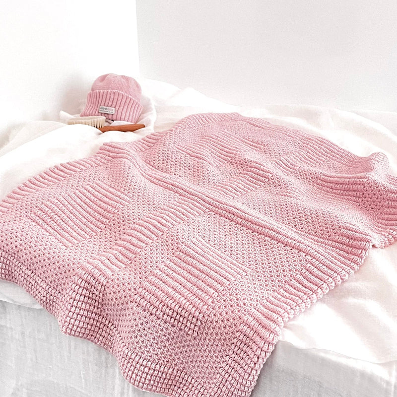 Blossom pink baby pram blanket on shelf with baby hair brush and matching pink beanie