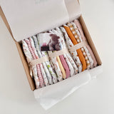 Box of baby dribble bibs with a teddy bear card on a light background