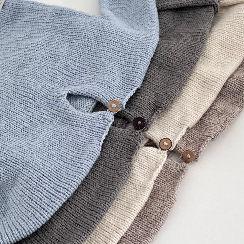 Stack of sweaters in blue, grey, and beige with wooden buttons.