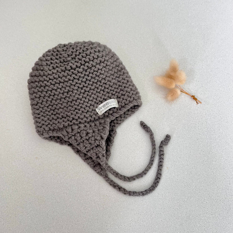 Knitted chunky knit baby hat mushroom colour on a light grey background