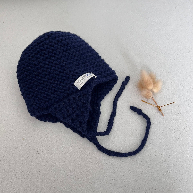 Knitted chunky knit baby hat navy colour on a light grey background