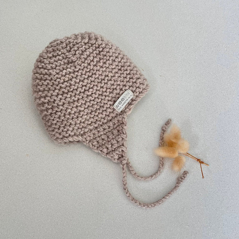 Knitted chunky knit baby hat oatmeal colour on a light grey background