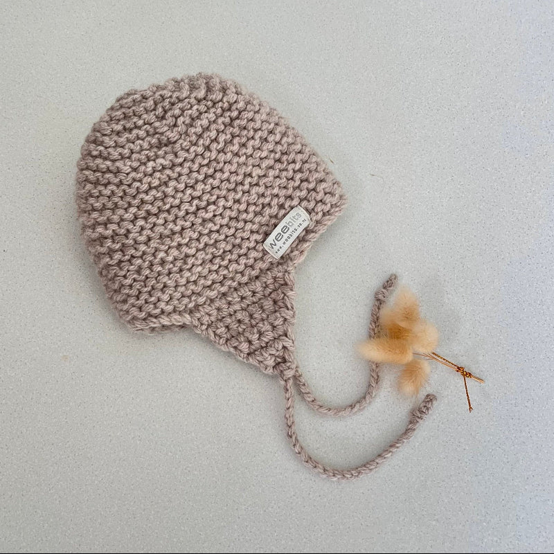 Knitted chunky knit baby hat oatmeal colour on a light grey background