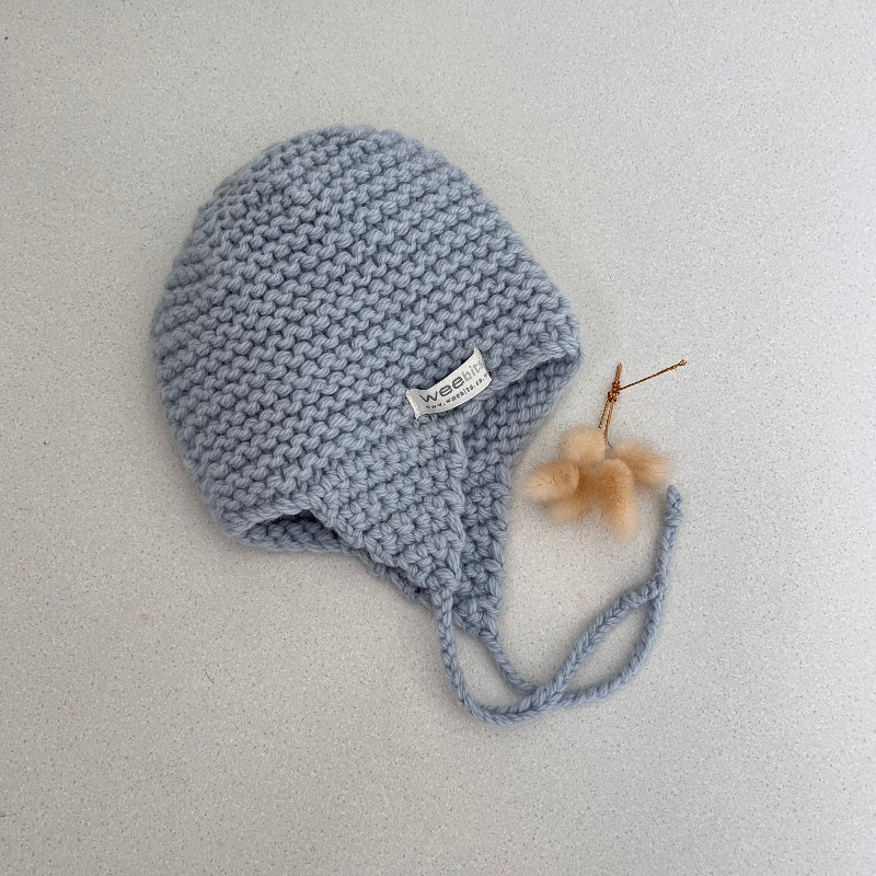 Knitted chunky knit baby hat blue colour on a light grey background