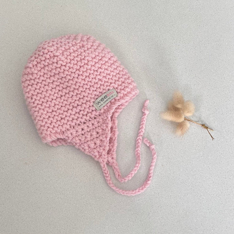 Knitted chunky knit baby hat pink colour on a light grey background