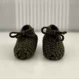 Pair of forest green baby chunky knit booties on a white surface with a striped background