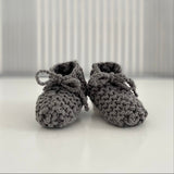 Pair of mushroom baby chunky knit booties on a white surface with a striped background