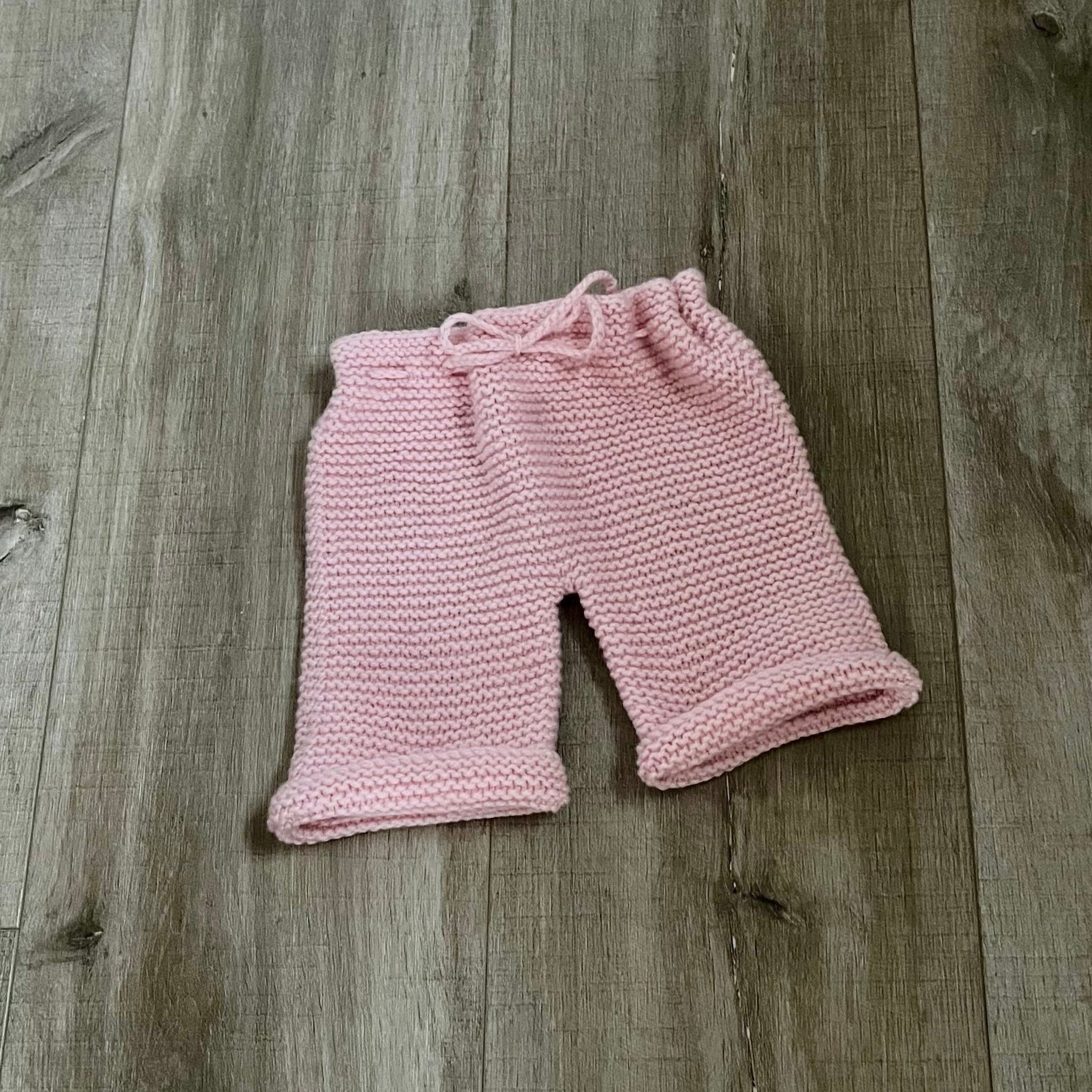 Pink knitted pants on a wooden surface