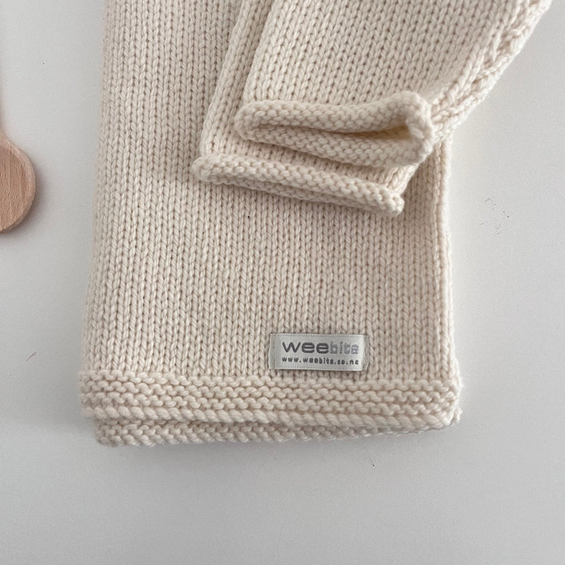 Knitted baby jumper with a visible brand label on a light background