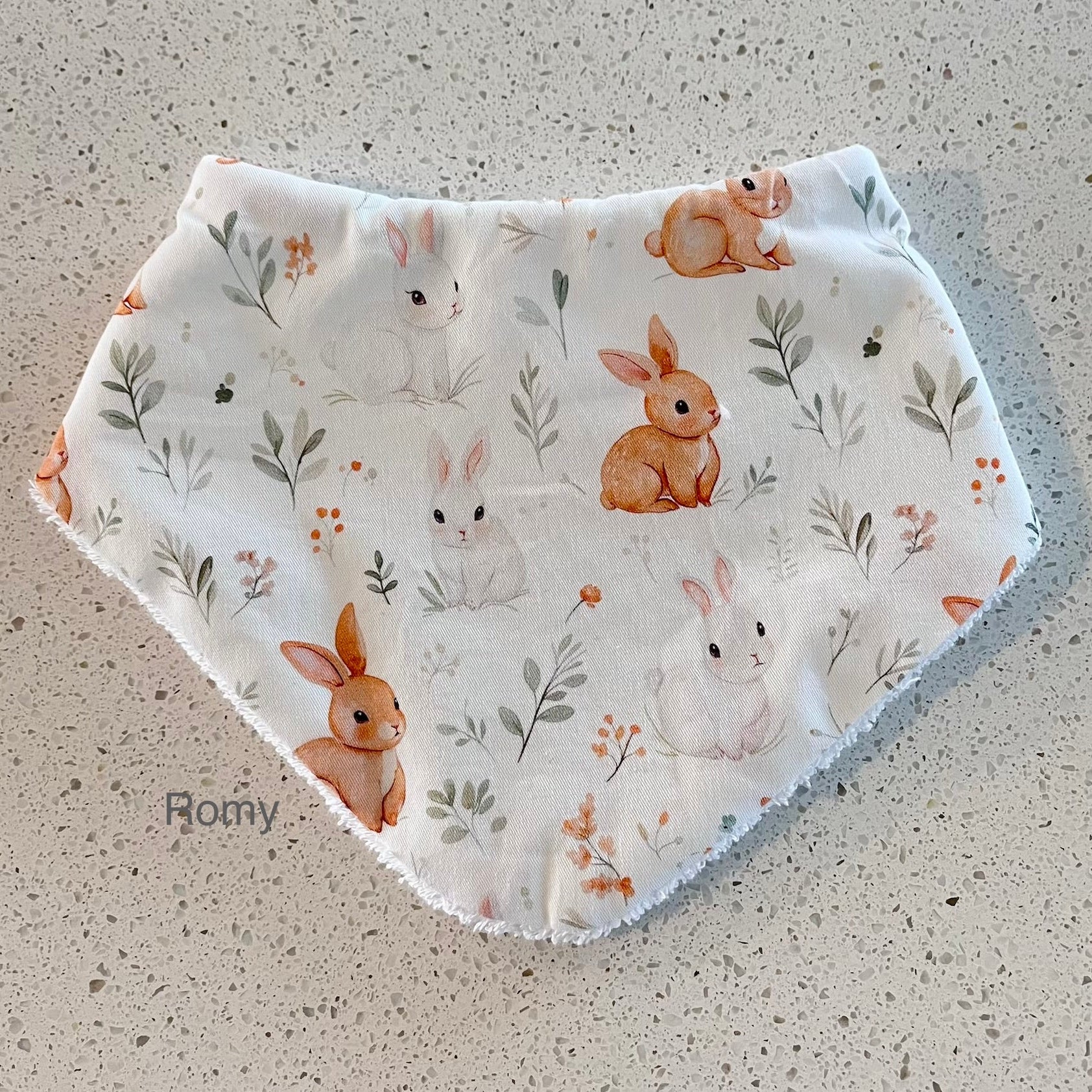 Baby bib with rabbit pattern on a textured surface