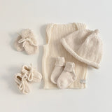 Baby clothing starter set with hat, shoes, and socks on a light gray background