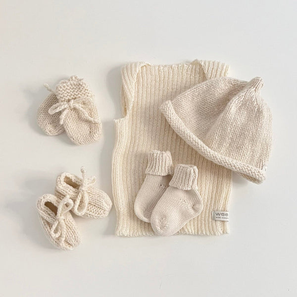 Baby clothing starter set with hat, shoes, and socks on a light gray background