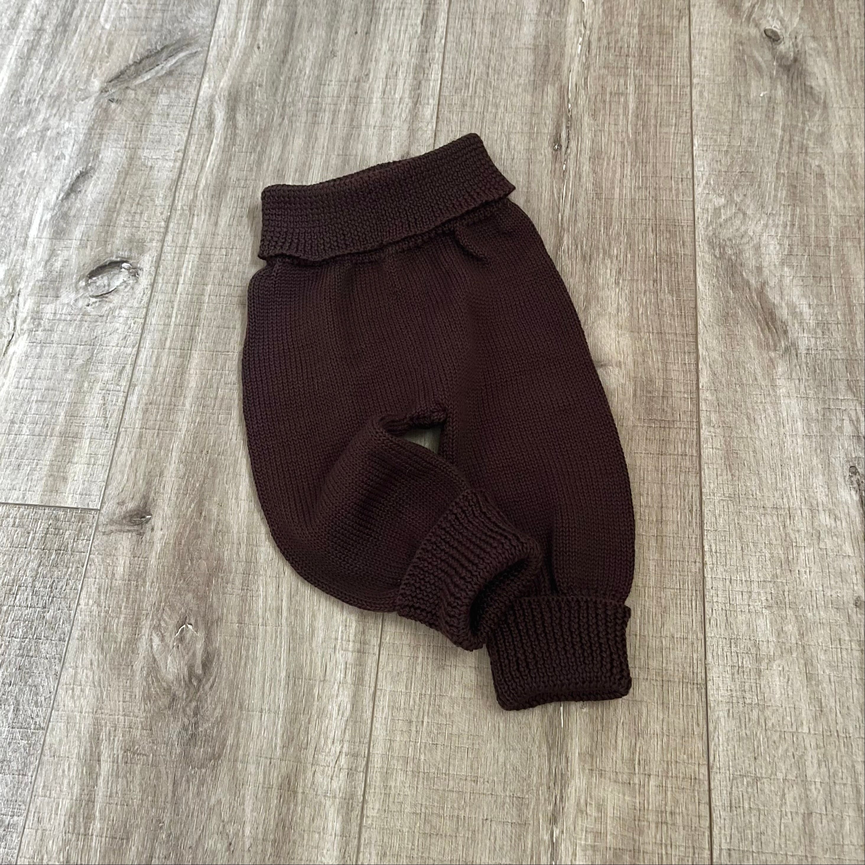 Baby brown knitted jodhpurs on wooden surface