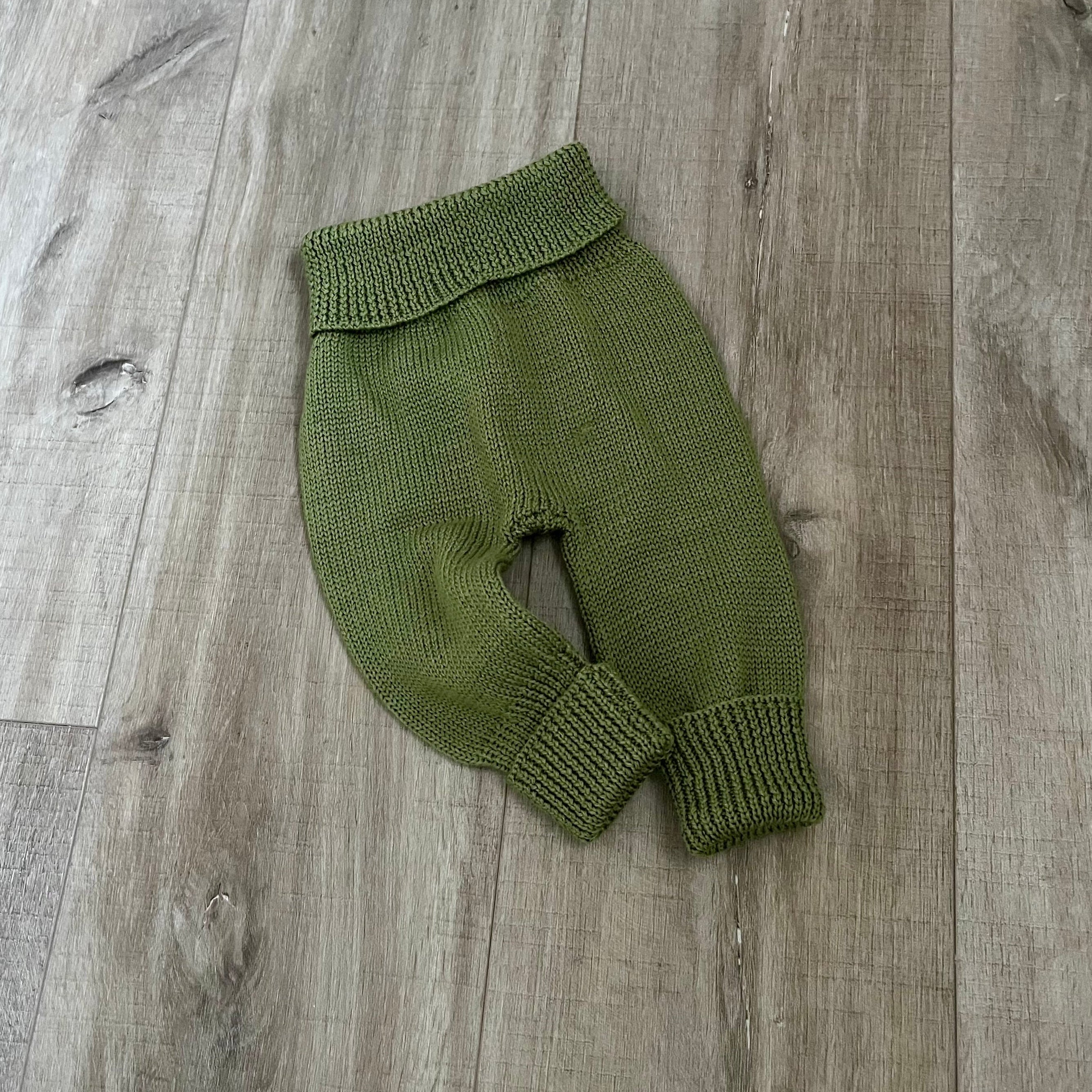 Baby moss knitted jodhpurs on wooden surface