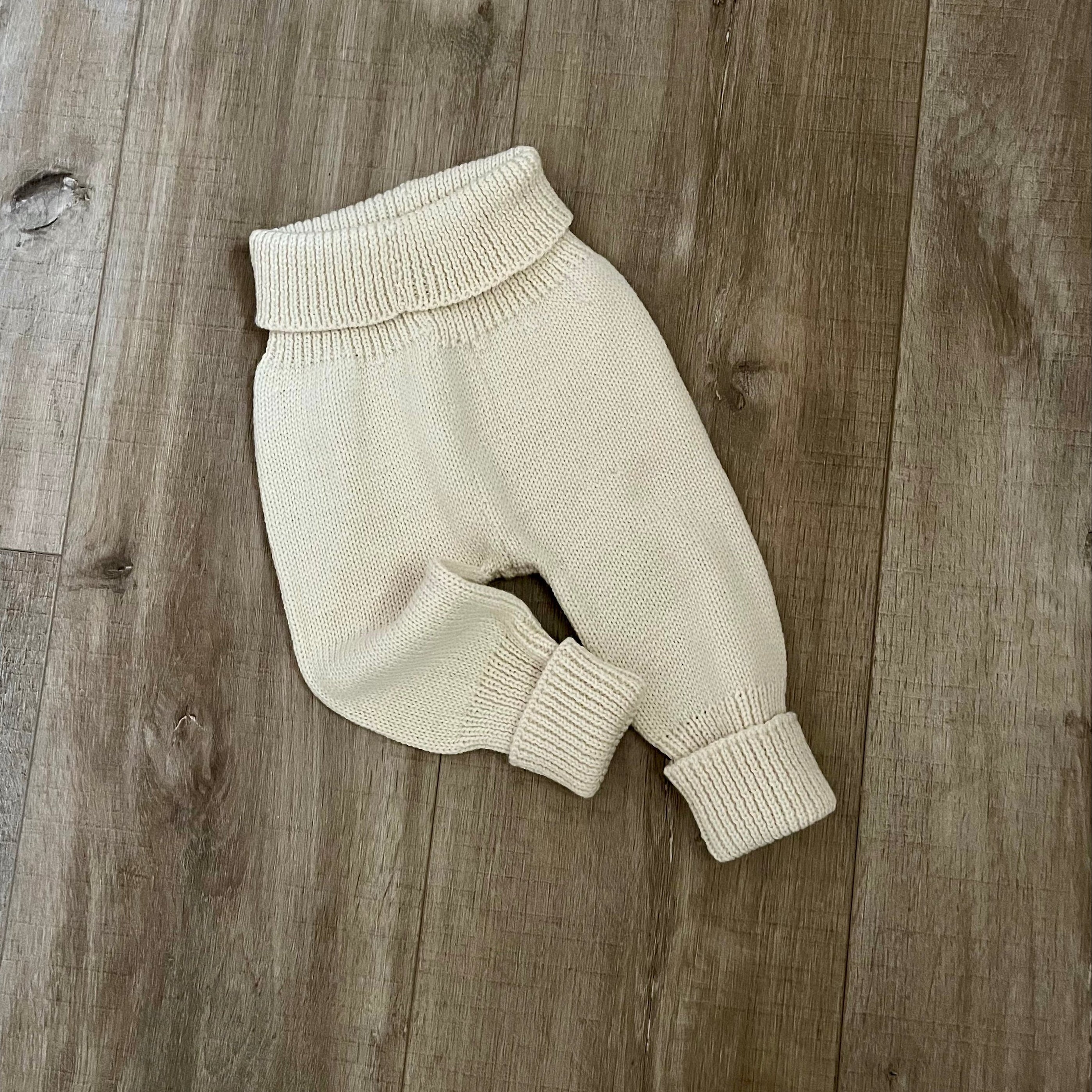 Baby natural colour knitted jodhpurs on wooden surface