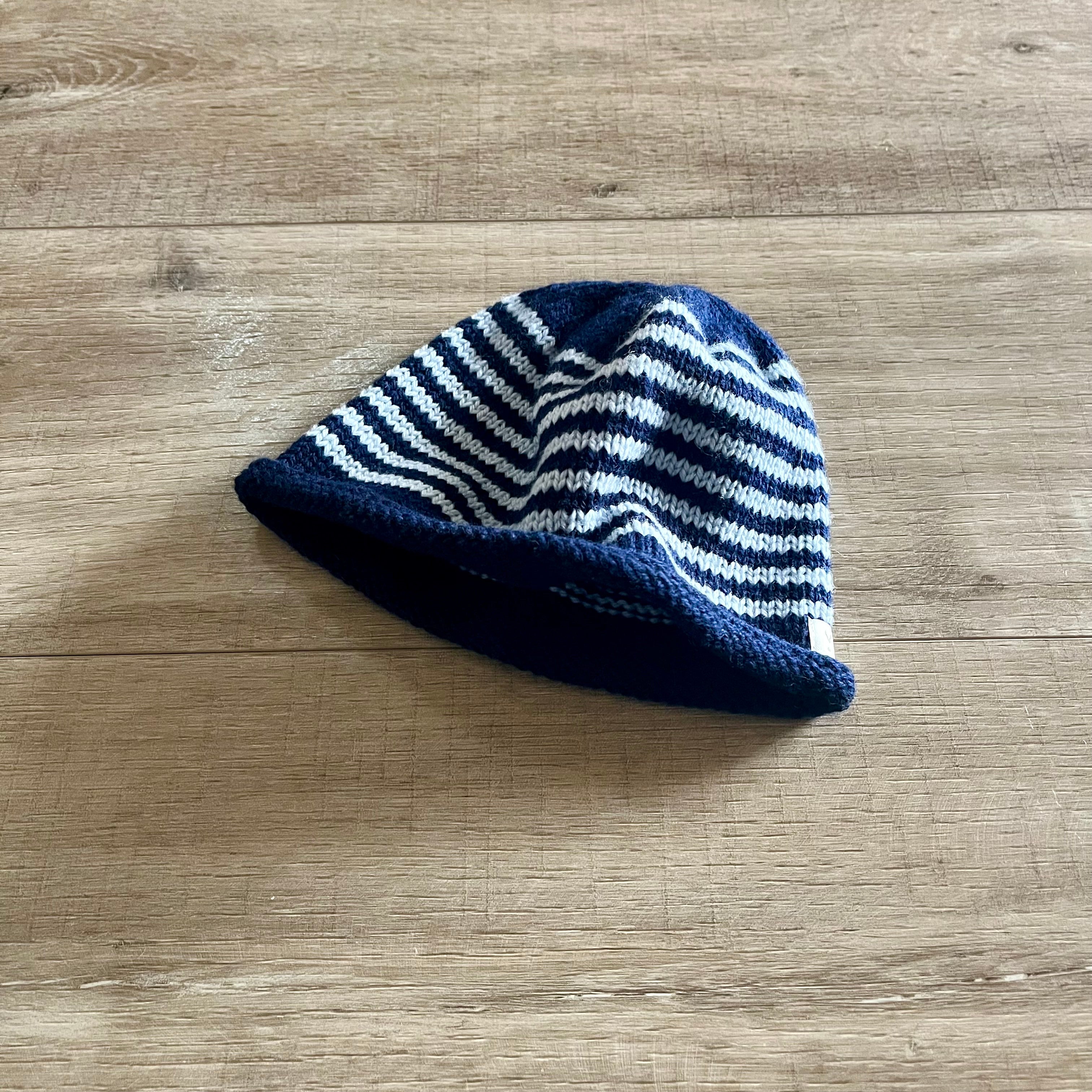 Blue and white striped knitted hat on a wooden surface