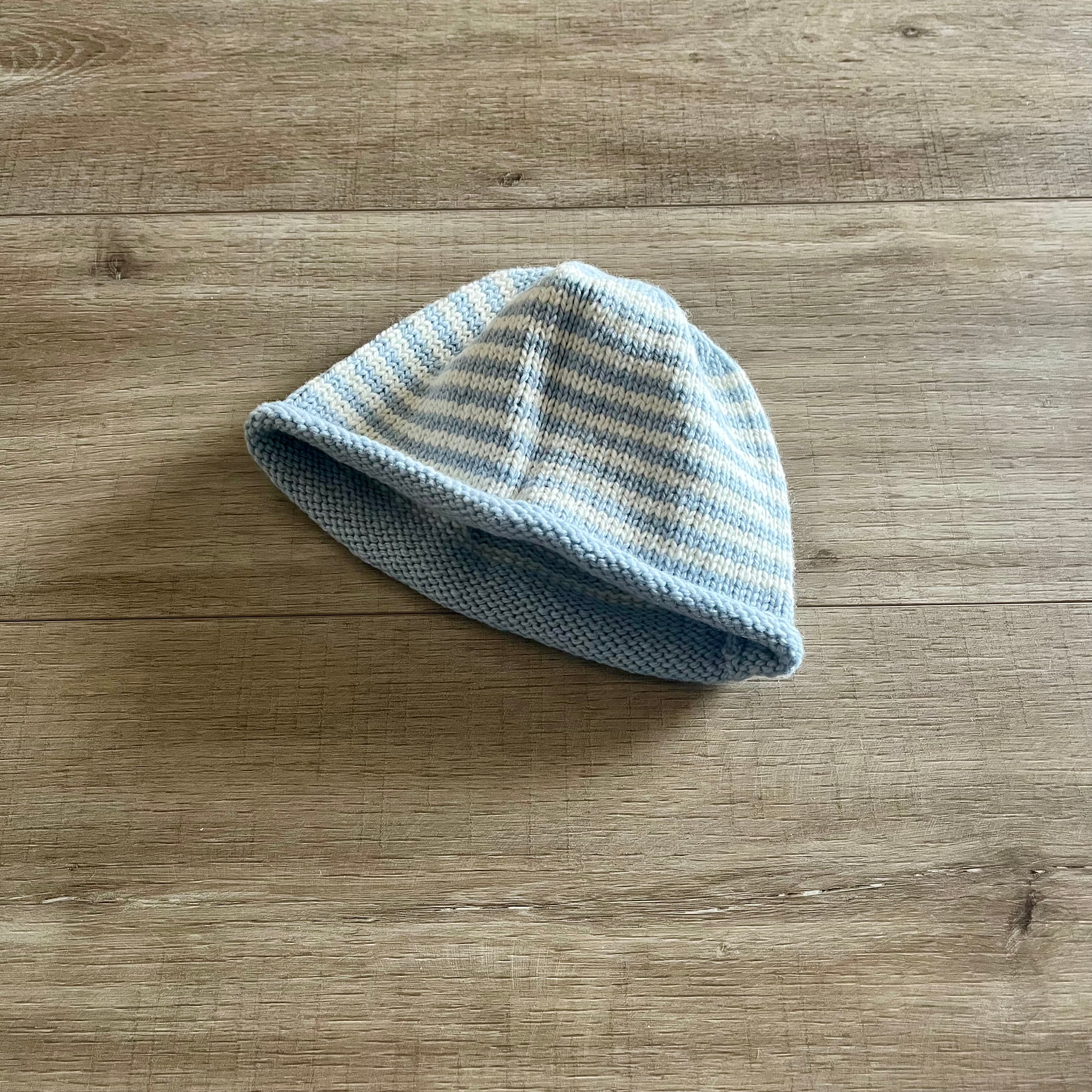 Blue and white striped baby hat on a wooden surface