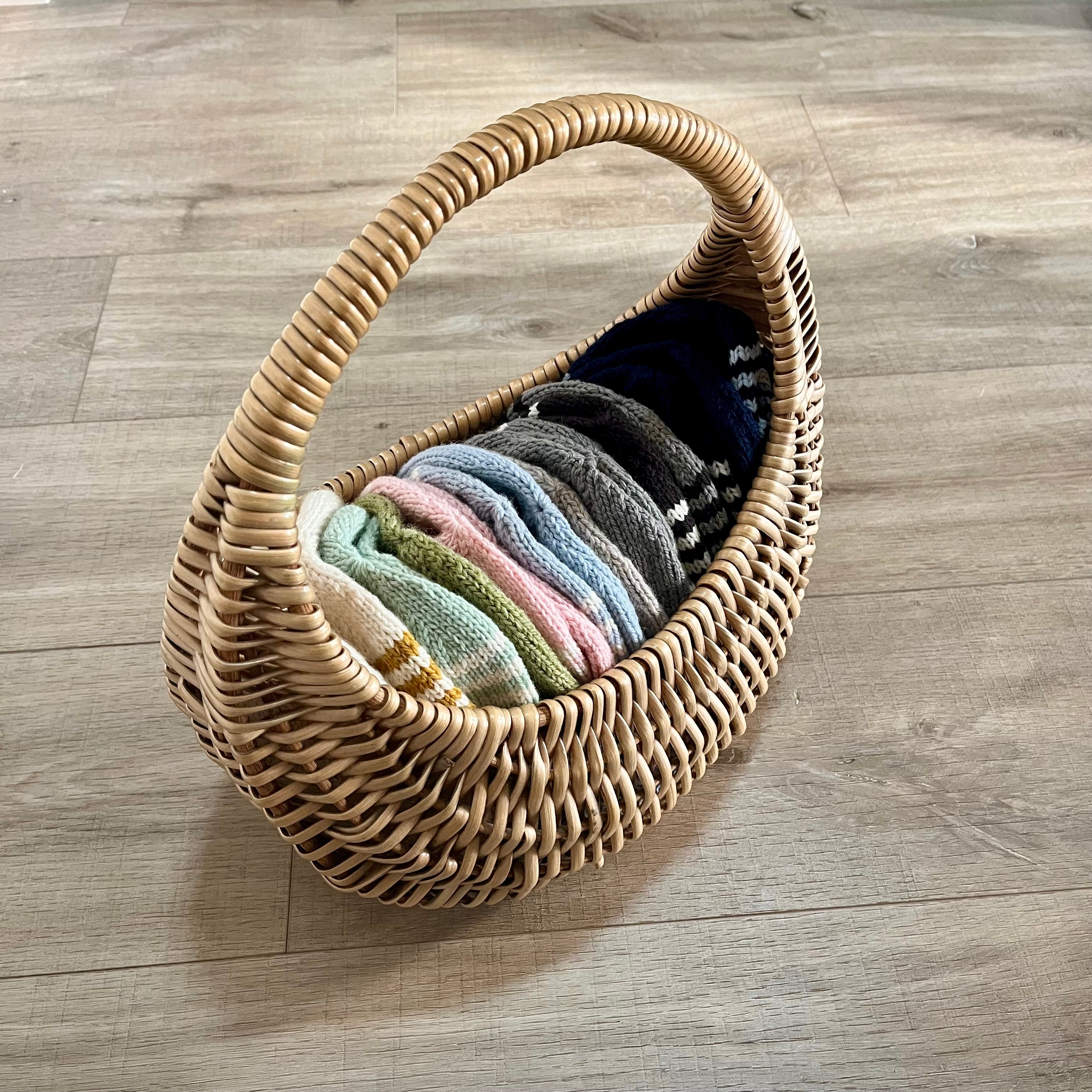 Kids knitted beanies in basket on wooden floor