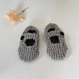 Pair of mushroom knitted baby booties on a light gray background