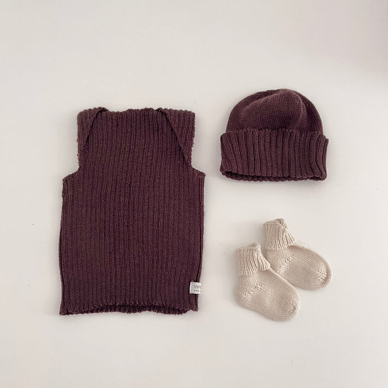 Baby brown vest, beanie, and socks on a light background